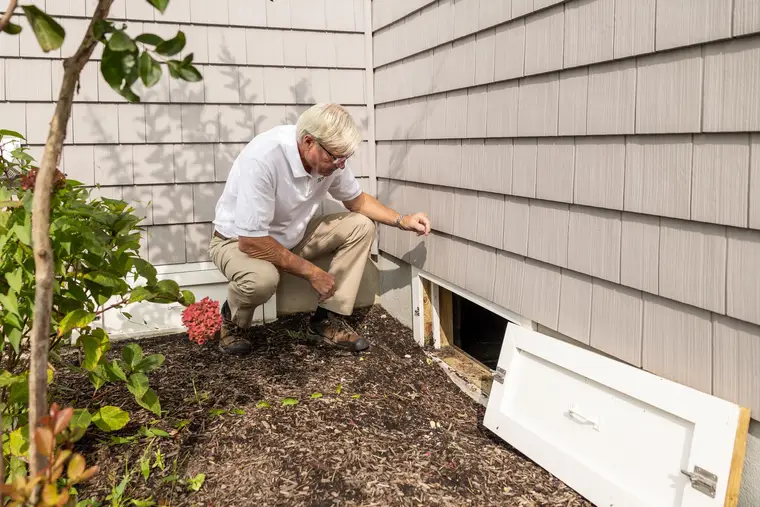 Checking a crawlspace through its access door at the side of a house