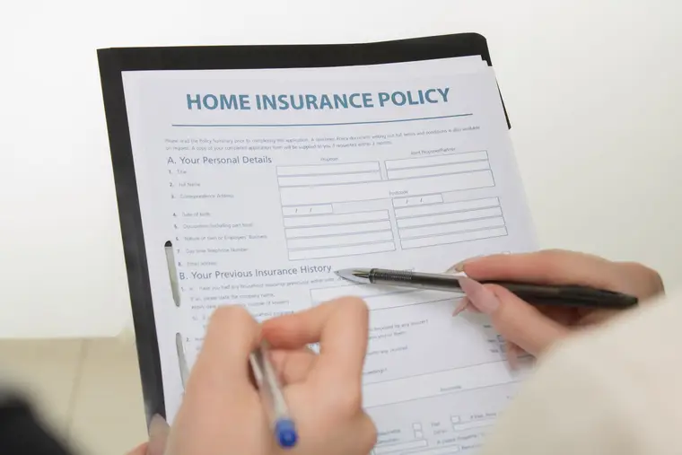 Filling out a home insurance policy form by hand