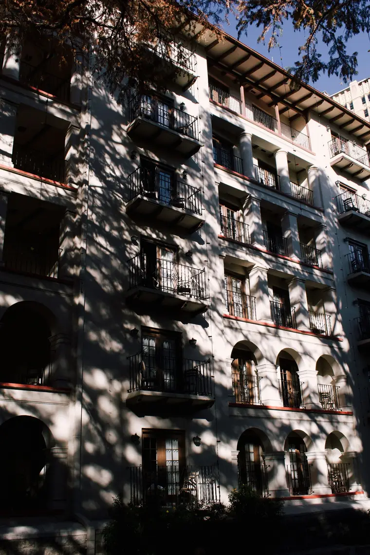 Balconied apartment building shaded by trees